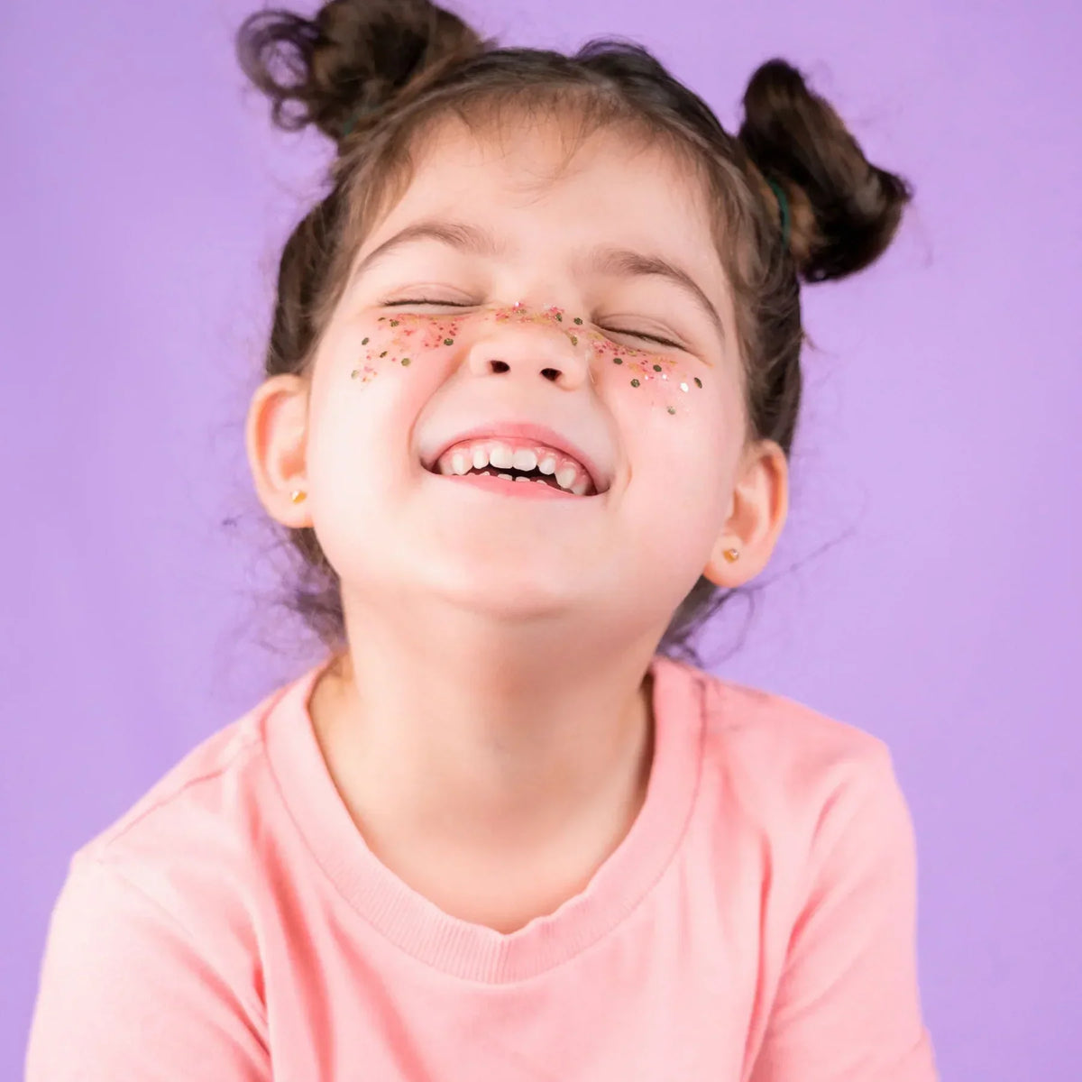 Petite fille souriante avec des paillettes sur les joues