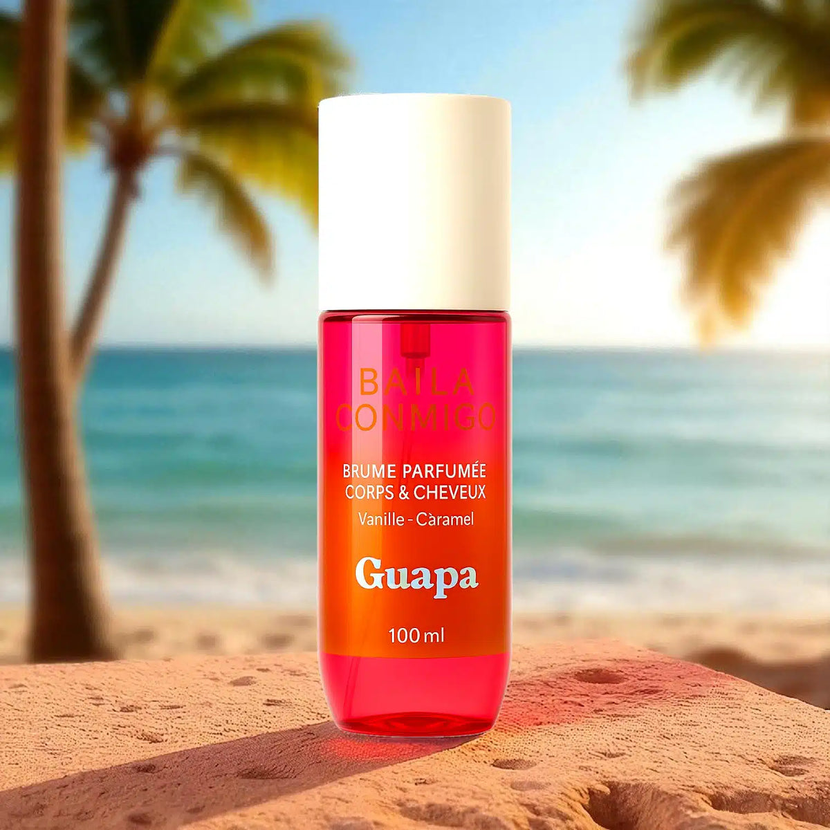 Brume parfumée Guapa vanille caramel posée sur un rocher devant une plage tropicale ensoleillée