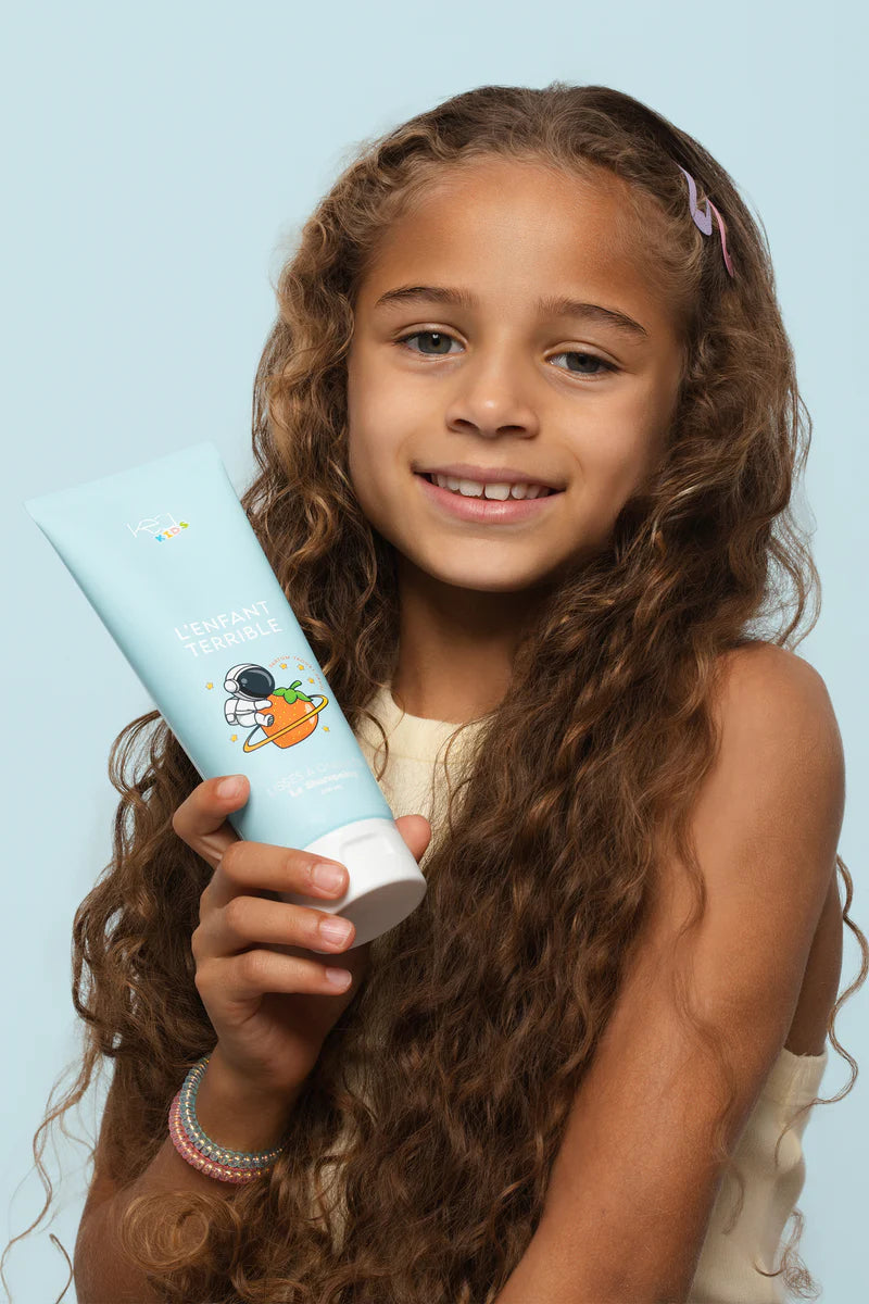 JEune fille avec son shampoing naturel pour cheveux lisses a ondules kea kids 