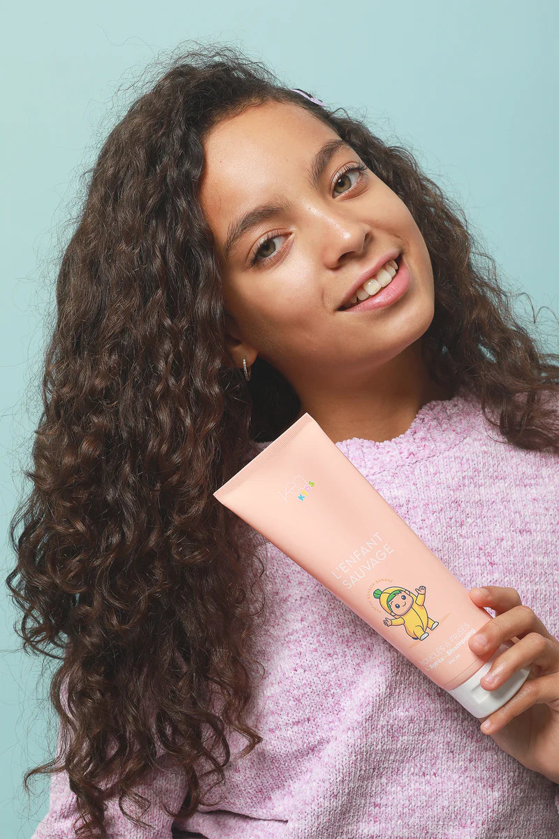 Petite fille avec son apres shampoing kea kids pour les cheveux boucles 