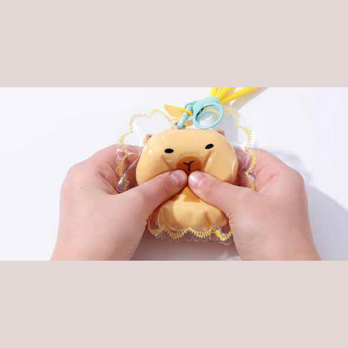 Porte-clés squishy capybara pressé entre les mains