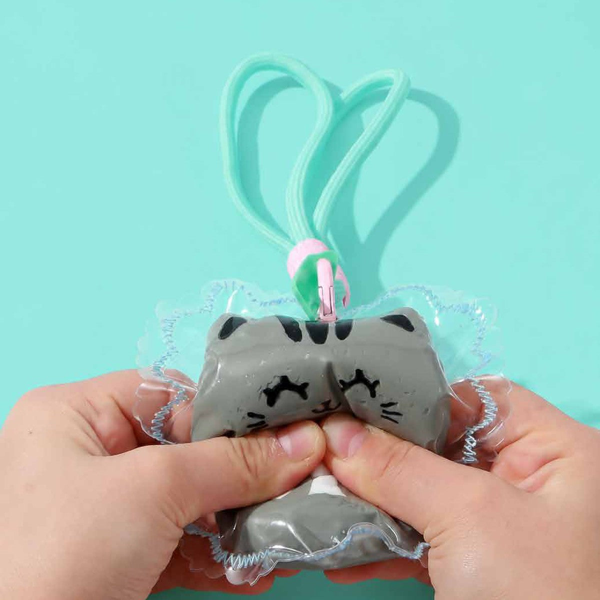 Porte-clés squishy chat gris pressé entre les mains